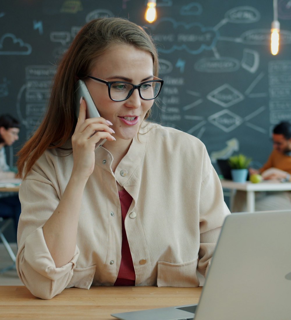 Corretora falando ao telefone em frente ao notebook