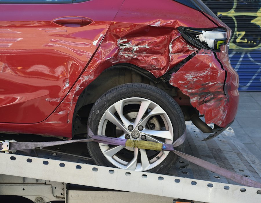 Carro com a lateral amassada sendo levado num guincho de plataforma